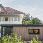 Nachhaltiger Anbau an ein Wohnhaus mit horizontaler Holzfassade und Eingangstür