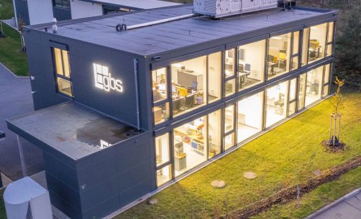 Luftbild eines beleuchteten Bürogebäudes in Holzbauweise am Abend